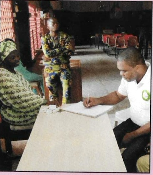 A KUTH volunteer signing the home's visitors' register with staff present