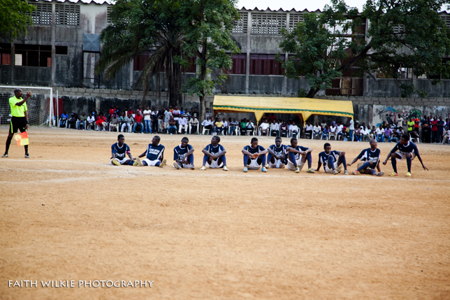 Team in navy jerseys seated on pitch before match