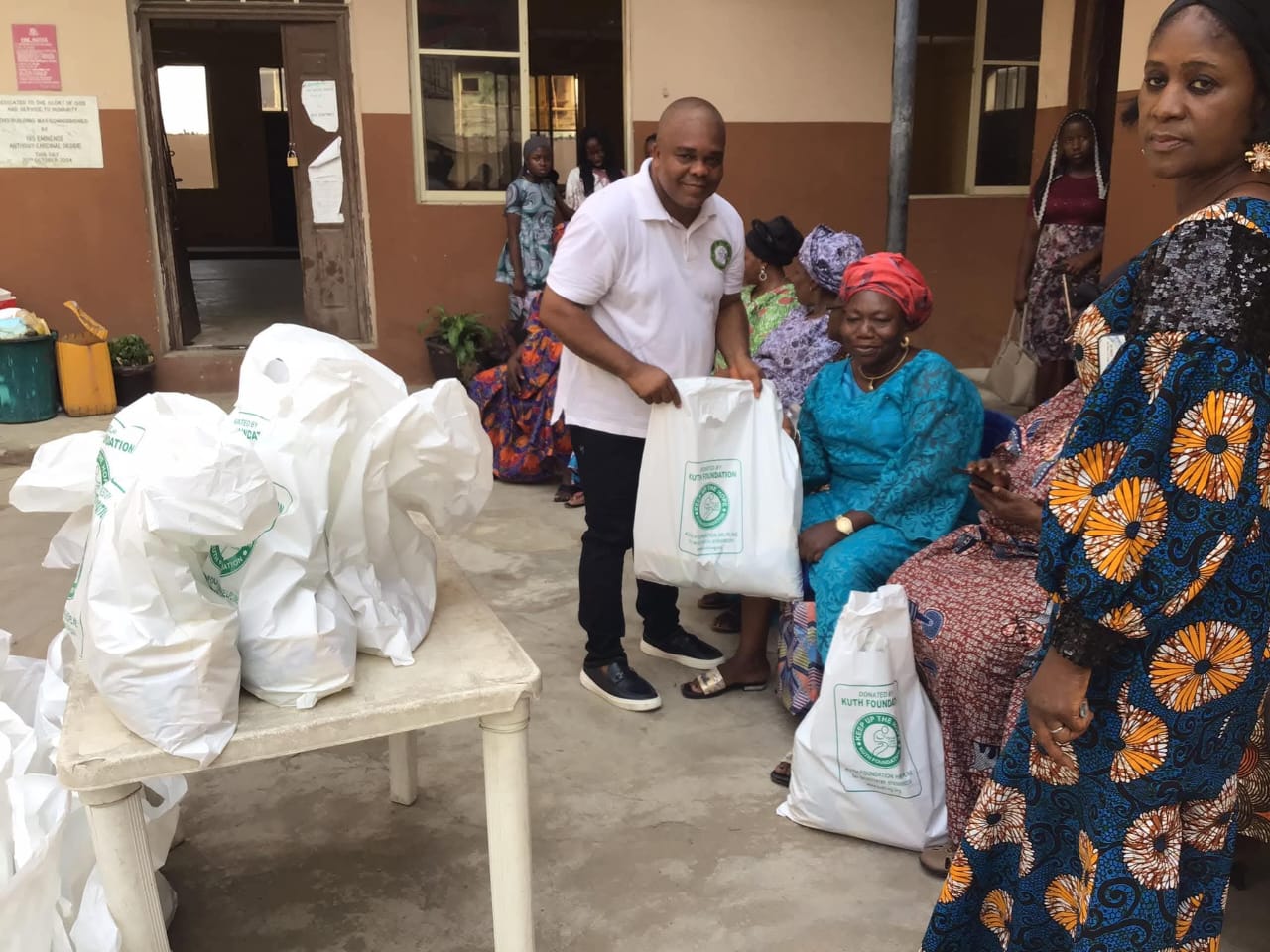 A KUTH volunteer handing a welfare bag to a widow